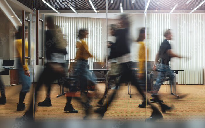 people walking by an office window