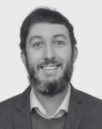 A bearded man wearing a white shirt and suit jacket