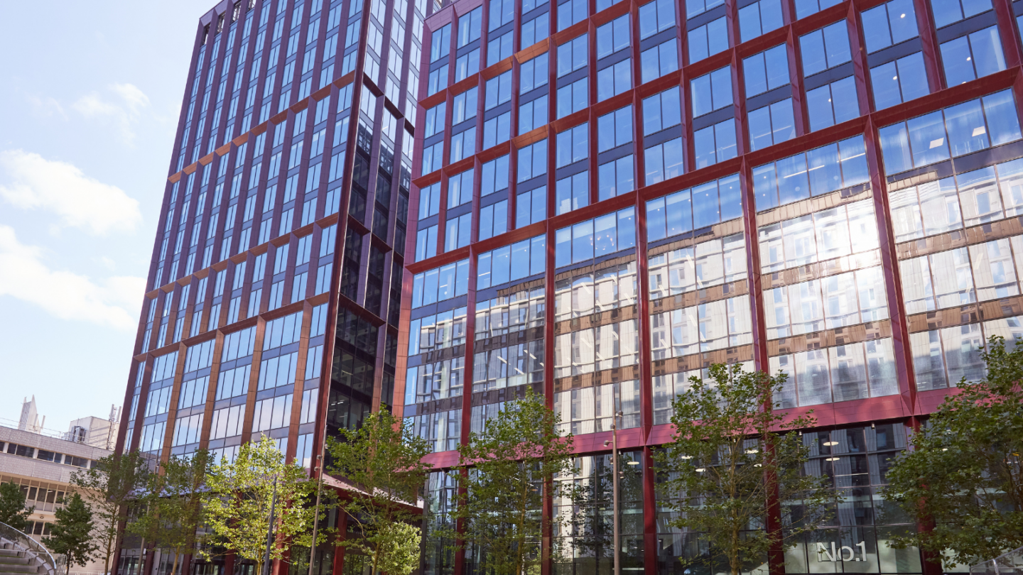 Large red building with large glass windows with trees below