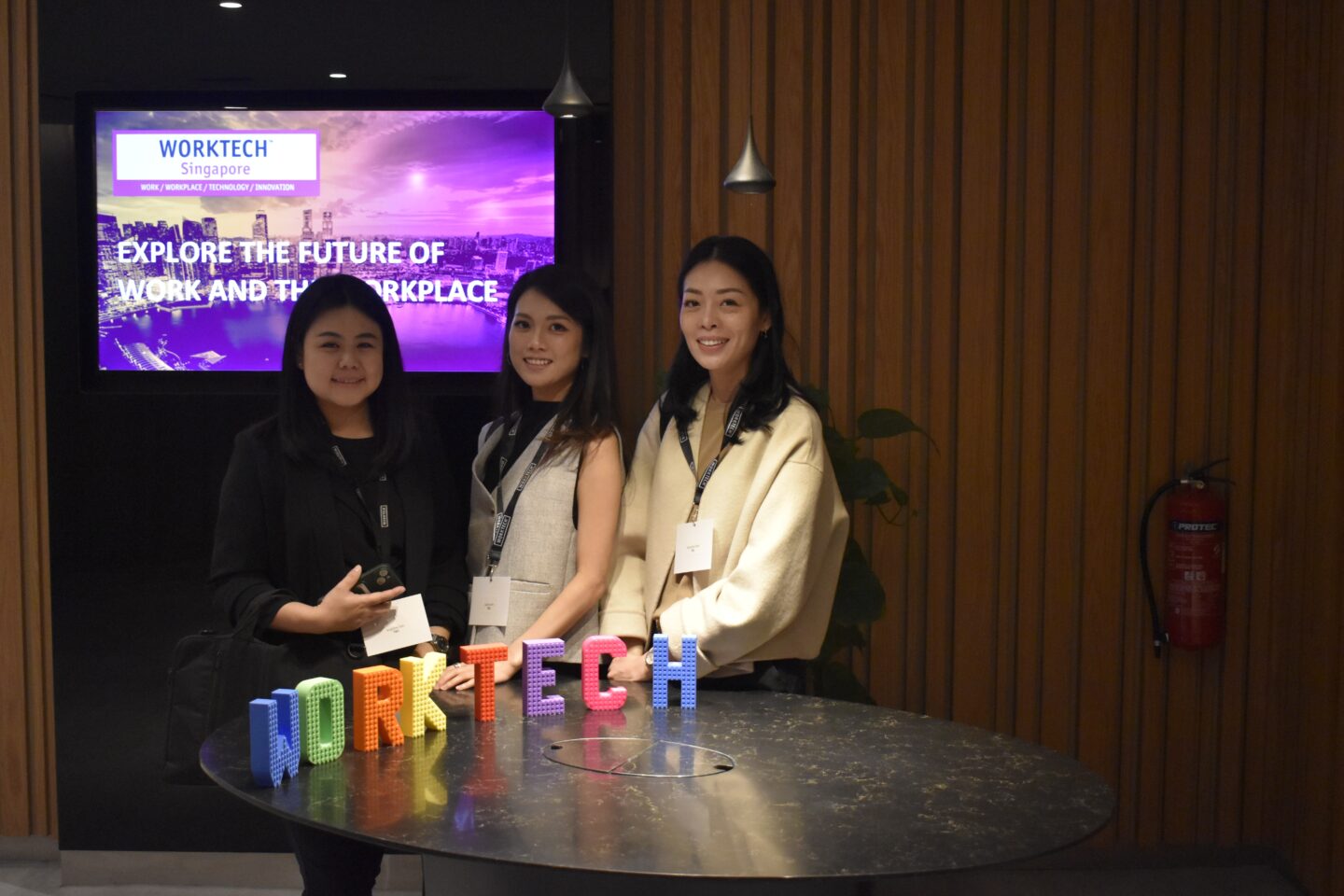conference attendees posing for a photo in front of a colourful sign spelling out WORKTECH and a backdrop of the event branding