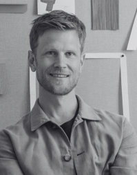 A short haired bearded man wearing an open-necked shirt