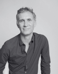 A headshot of a man with short hair wearing a dark shirt.