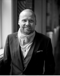 A short haired man wearing a necktie and suit jacket.