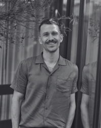 A short haired man with a moustache wearing a cause short sleeved shirt