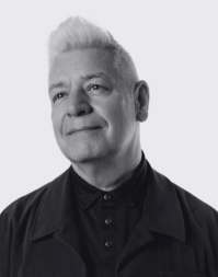 A short haired man wearing a dark buttoned up shirt