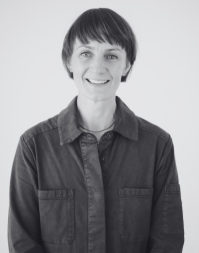 A short, haired woman wearing a dark coloured work shirt.