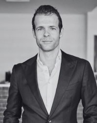 A short haired man wearing an open neck shirt and suit jacket