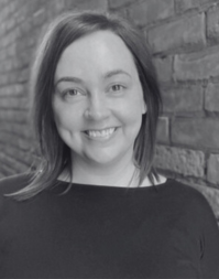 A woman with shoulder length dark hair wearing a dark coloured round neck top
