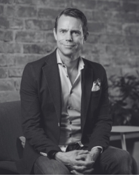 A business man wearing an open necked shirt and suit jacket