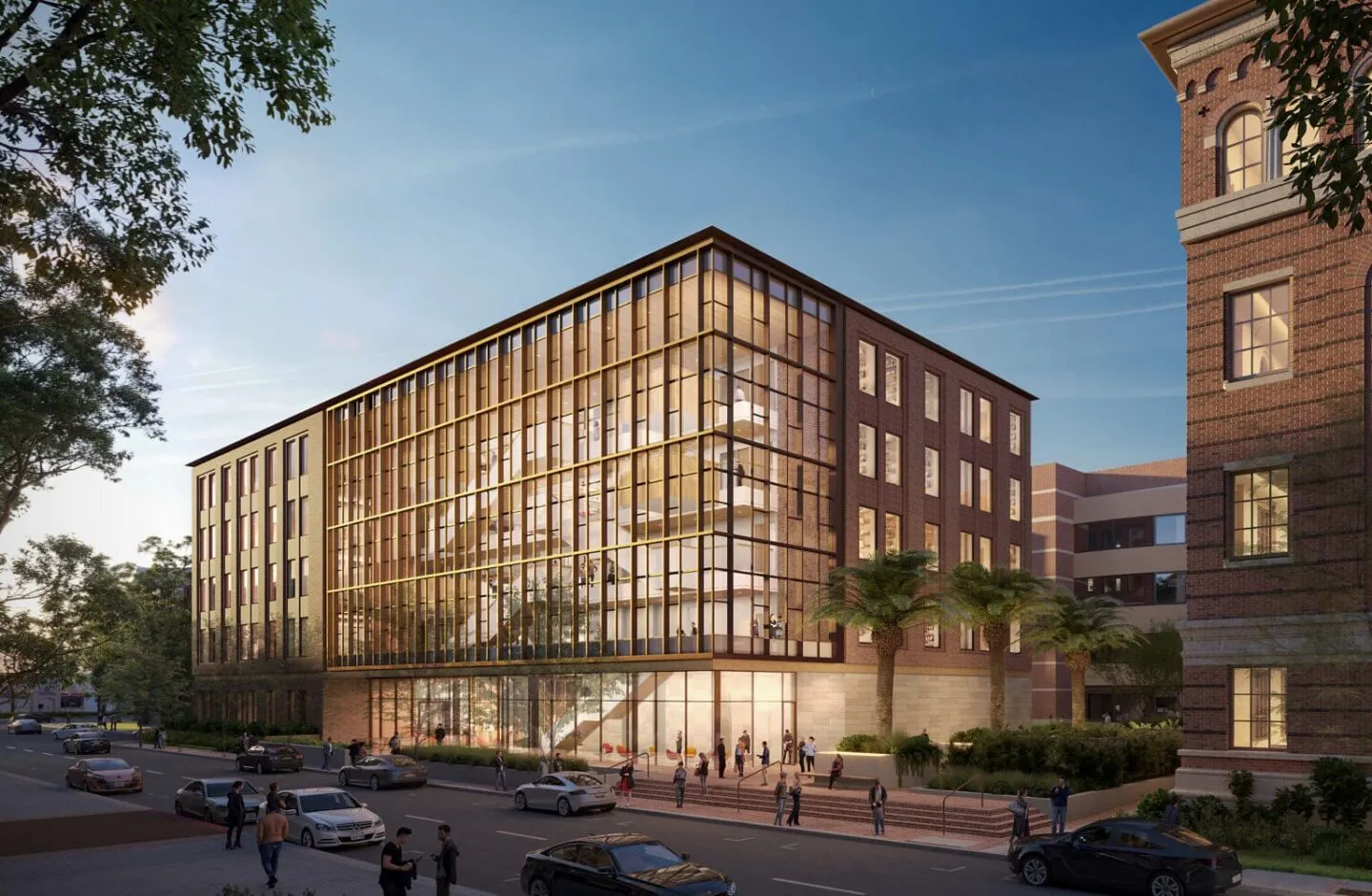 render image of ginburg building at USC campus. A brick building with large glass windows emitting yellow light in a city scene