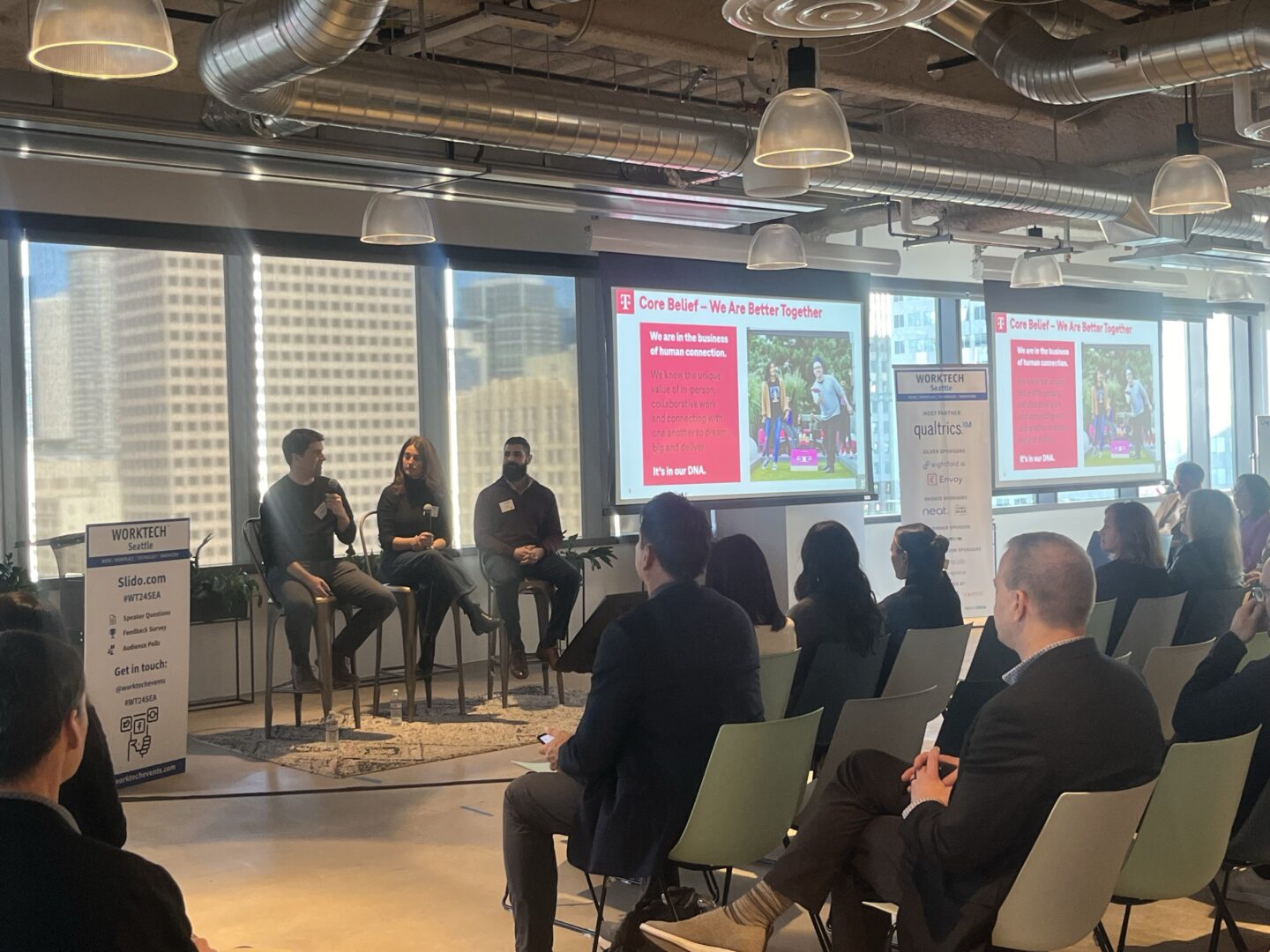 panel of speakers at WORKTECH Seattle sat on stage in front of a seated audience in a brightly lit room